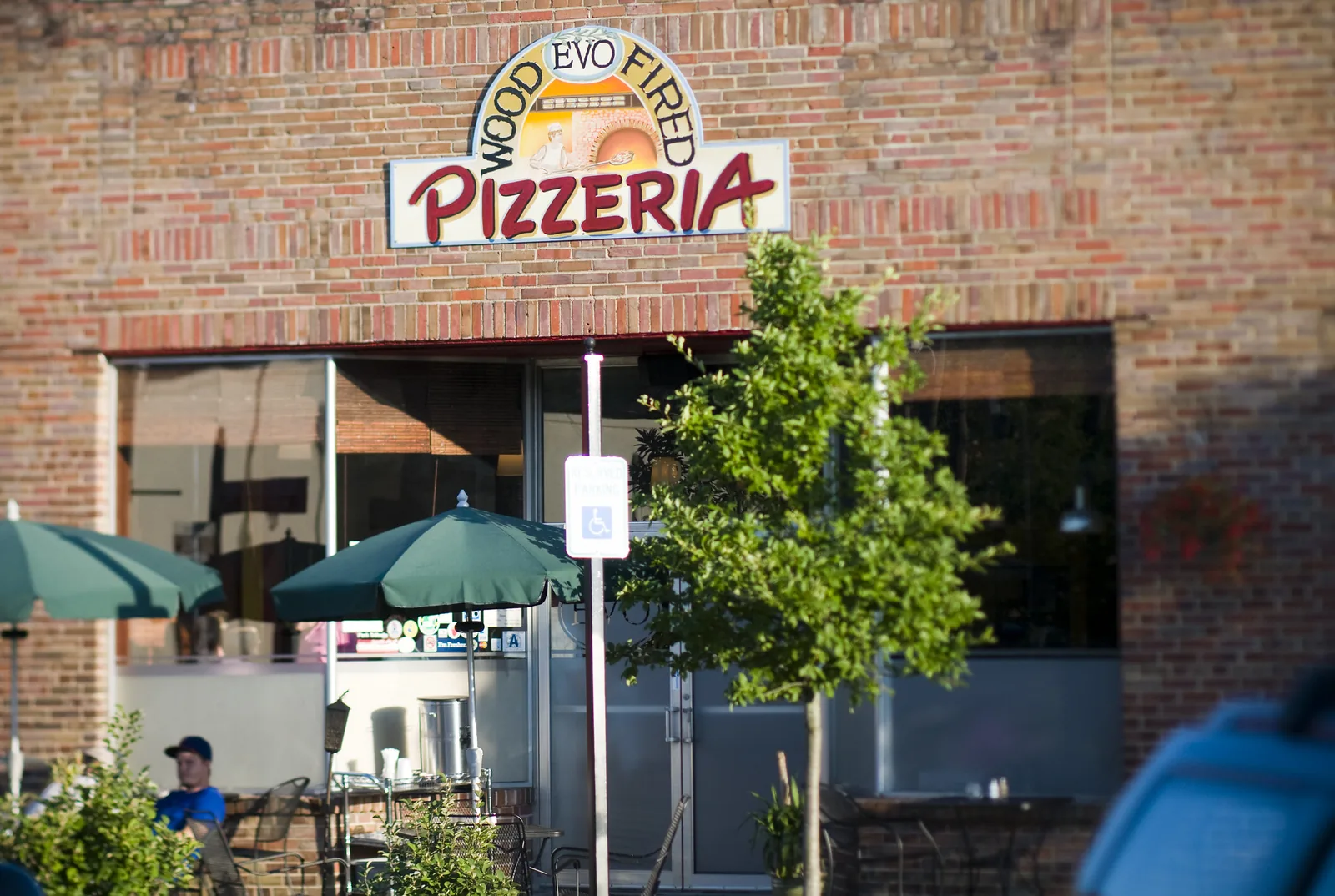 Diners sit under green umbrellas on the patio of EVO Pizzeria on East Montague Avenue in Park Circle.