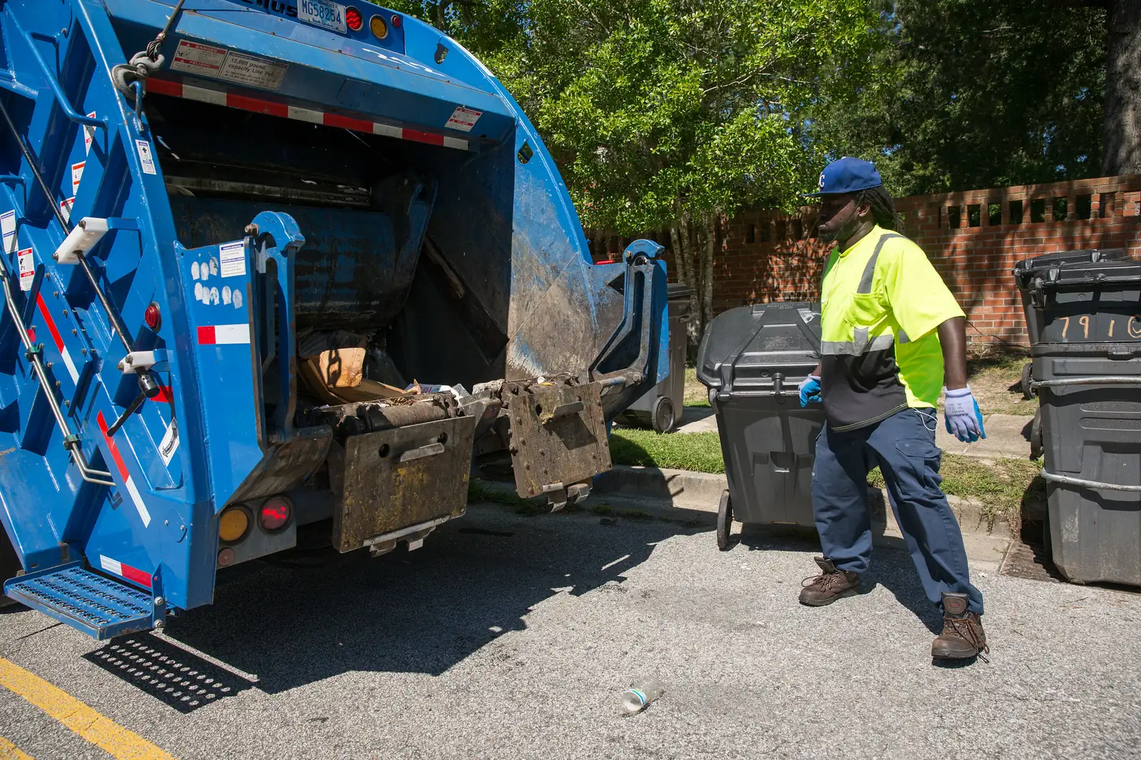 A North Charleston sanitation worker steps back from a city garbage truck after emptying roll carts on a residential street.