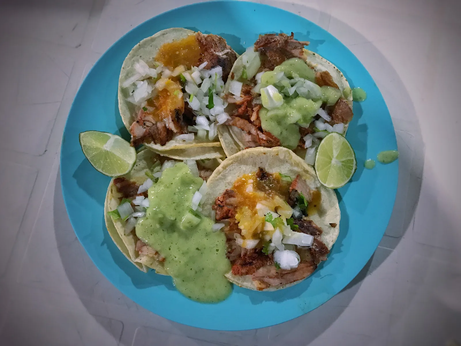 A plate of al pastor tacos with onion, cilantro, salsa and lime. The photo was taken in Tulum, Mexico, not in North Charleston.