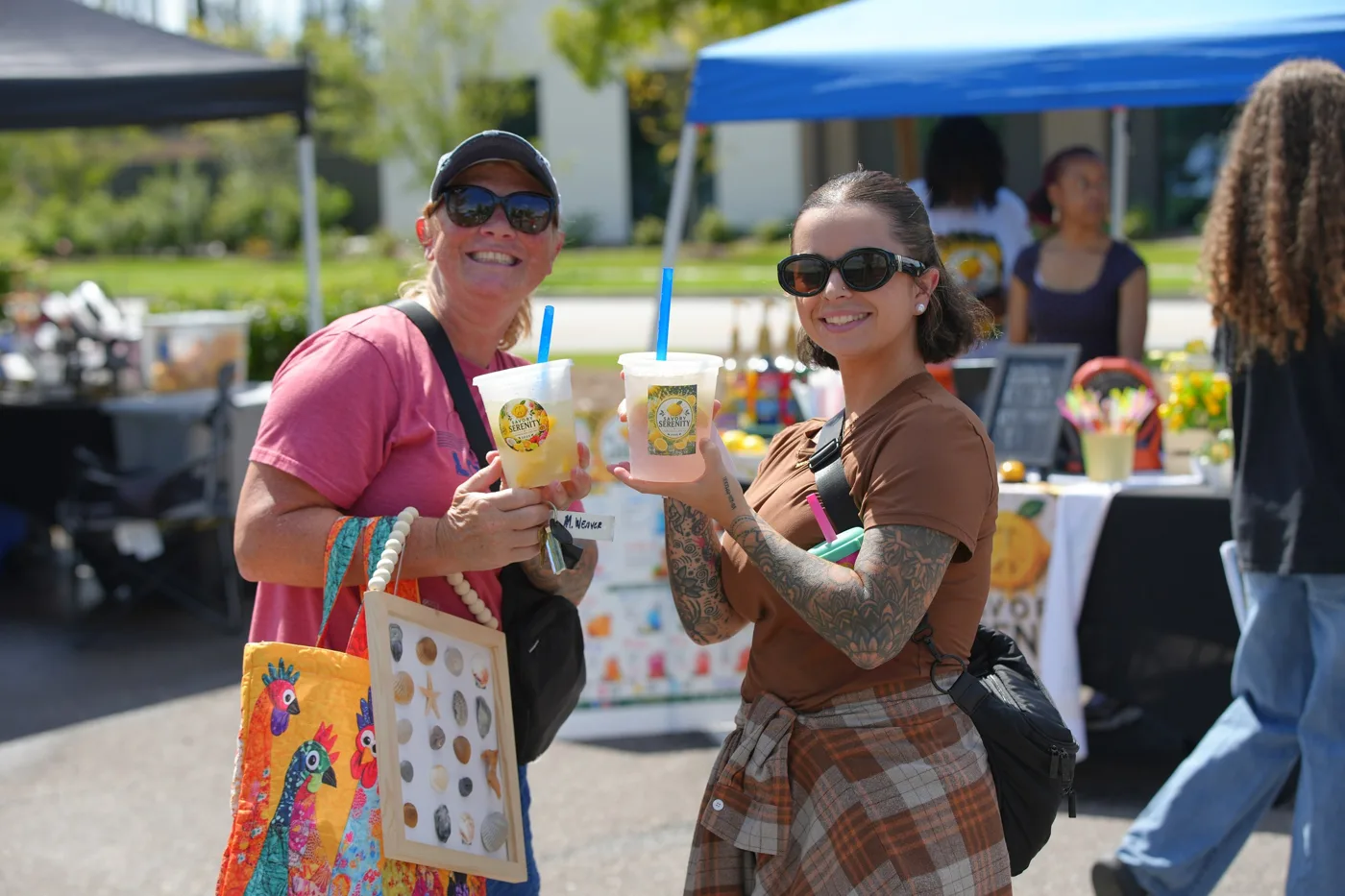 Two shoppers hold up their drinks at Summerville Destination Market.