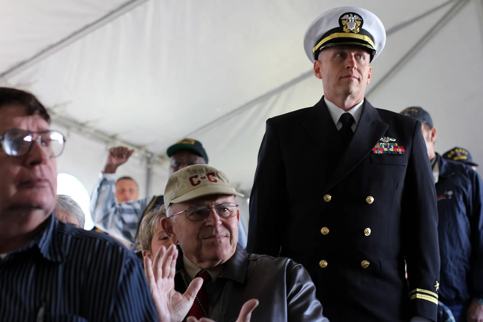 A Navy officer and veterans stand under the tent at the City of North Charleston's Veterans Day tribute at Park Circle; the tribute is now held at the Performing Arts Center.